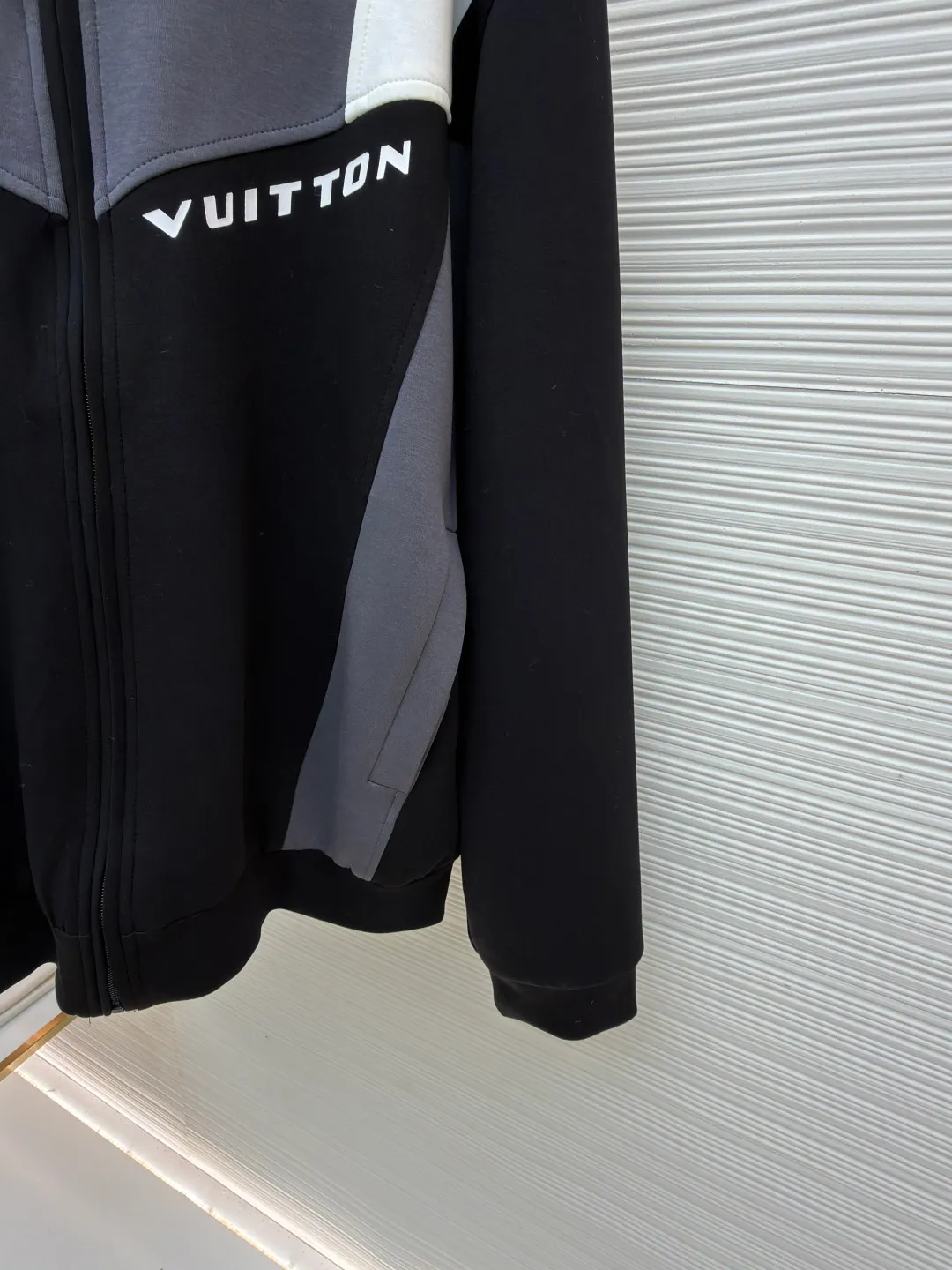 LOUIS VUITTON Spliced jogging sweatshirt long-sleeved sweatshirt ●Original version: Purchased and developed by 13126 ●Item number: 1682019-B70 ●Fabric: 100% cotton ●Technology: Made by positioning cutting machine ●Color: black, gray and white ●Version: fitted version ●Weight: about 1015 grams ●Size: S-M-L-XL ●Description: This Louis Vuitton color-blocked jacket is made of high-elastic composite knitted fabric (polyester fiber + spandex blend), which has been treated with matte brushing, giving it both stiffness and skin-friendly feel. The body of the garment adopts geometric color-blocking cutting technology: black, gray, and white pieces are spliced ​​diagonally in a V-shape, and the edges are processed by "laser seamless fit + same-color overlocking" to ensure smooth seams without any irritation. The "VUITTON" logo on the chest uses a three-dimensional silicone imprinting process. It is first laid with a low-temperature setting glue layer and then covered with a matte coating to take into account the three-dimensionality and washability of the logo. The neckline is a stand-up collar design with built-in elastic lining reinforcement; the zipper is made of brand-customized metal, and the chain teeth are the same color as the fabric; the cuffs and hem are equipped with high-elastic ribbing, and the overall shape is ergonomically optimized to suit daily casual scenes. The overall wiring is straight and delicate, the fabric is comfortable and soft, and the color is consistent without color difference. It can be matched with the same style to create a fashionable look and control various occasions. Customized accessories, complete with three standards, same style for men and women!